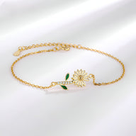 Bracelet fin en or avec charm marguerite et petites feuilles vertes en émail.