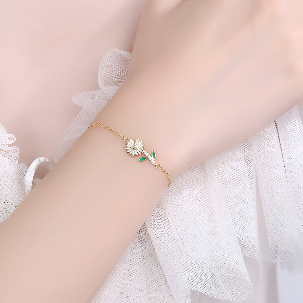 Bracelet fin en or avec charm marguerite émaillée blanche et tige verte délicate.