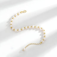 Bracelet en argent avec perles naturelles blanches et détails dorés, fermoir ajustable.