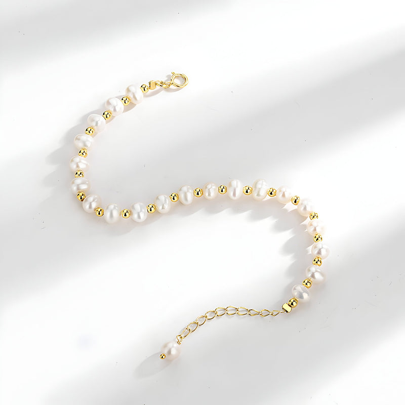 Bracelet en argent avec perles naturelles blanches et détails dorés, fermoir ajustable.