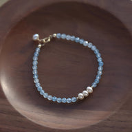 Bracelet fin en argent sterling avec perles d'aigue-marine bleues et trois perles blanches centrales.