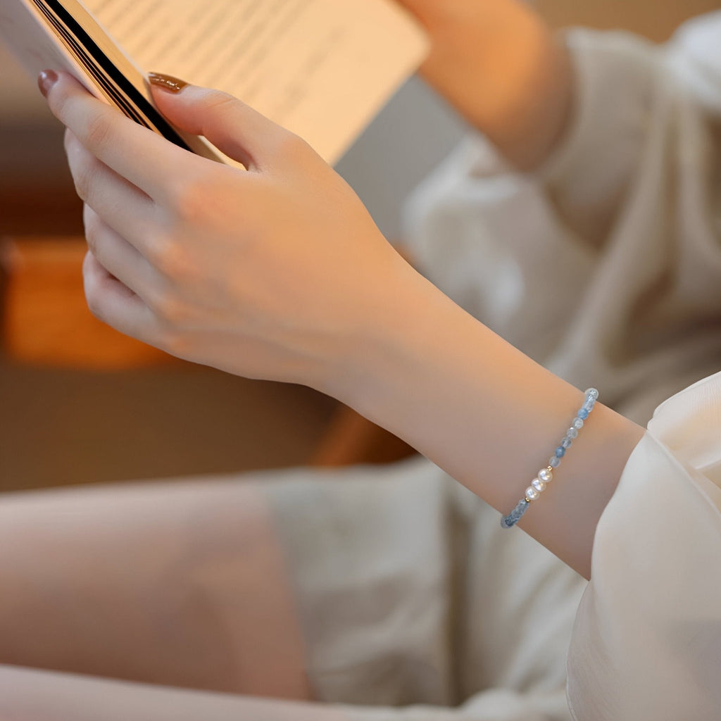 Bracelet fin en argent sterling avec petites pierres bleues d'aigue-marine sur poignet féminin.