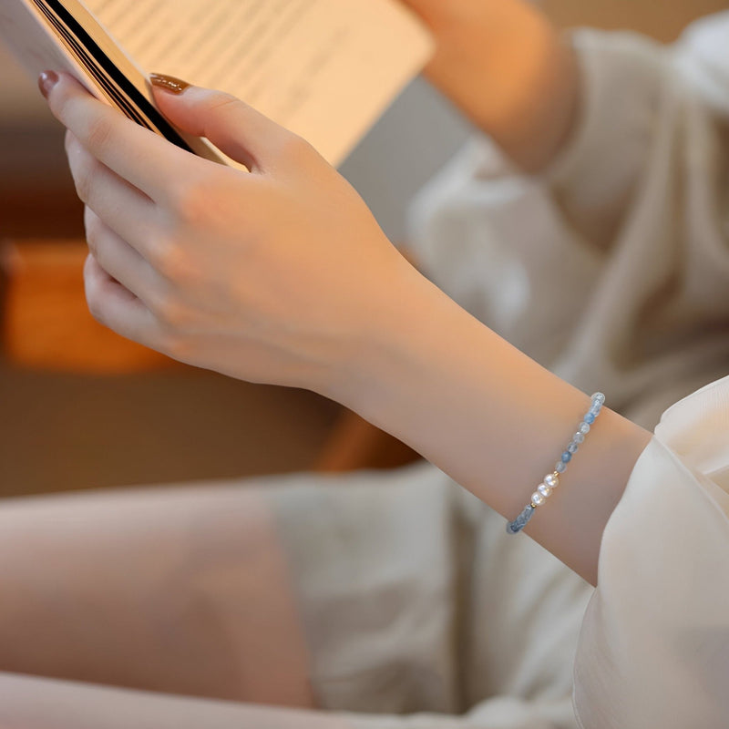 Bracelet fin en argent sterling avec petites pierres bleues d'aigue-marine sur poignet féminin.