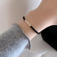Bracelet fin en argent sterling avec petites pierres d'onyx noires, style délicat pour femme.