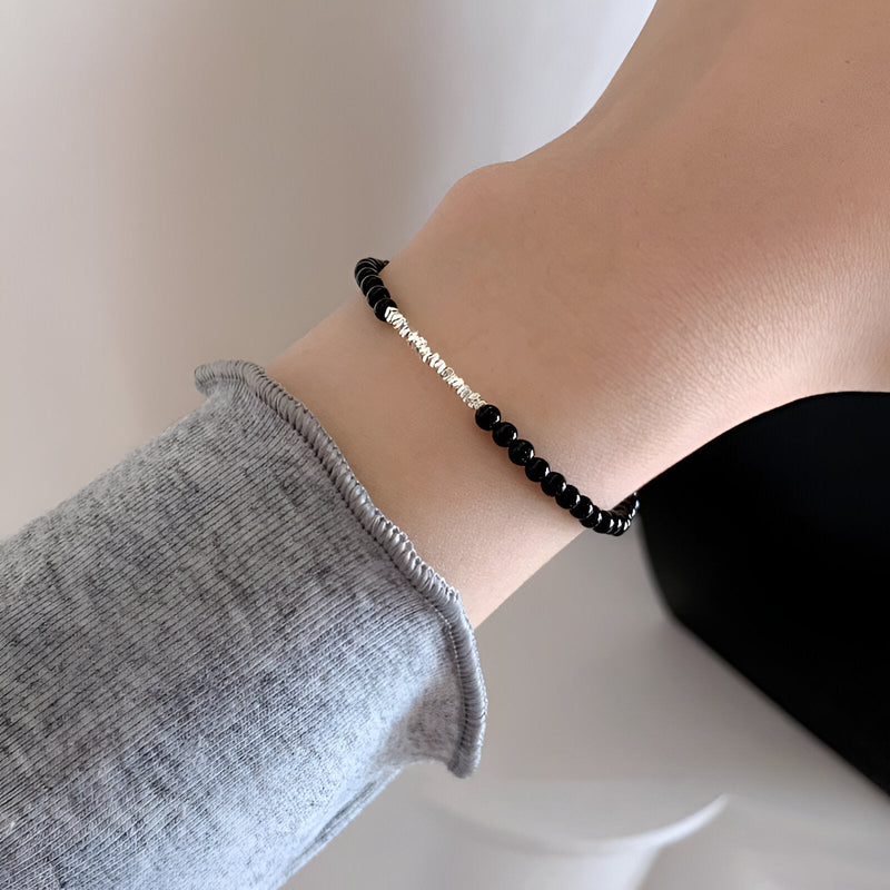 Bracelet fin en argent sterling avec petites pierres d'onyx noires, style délicat pour femme.