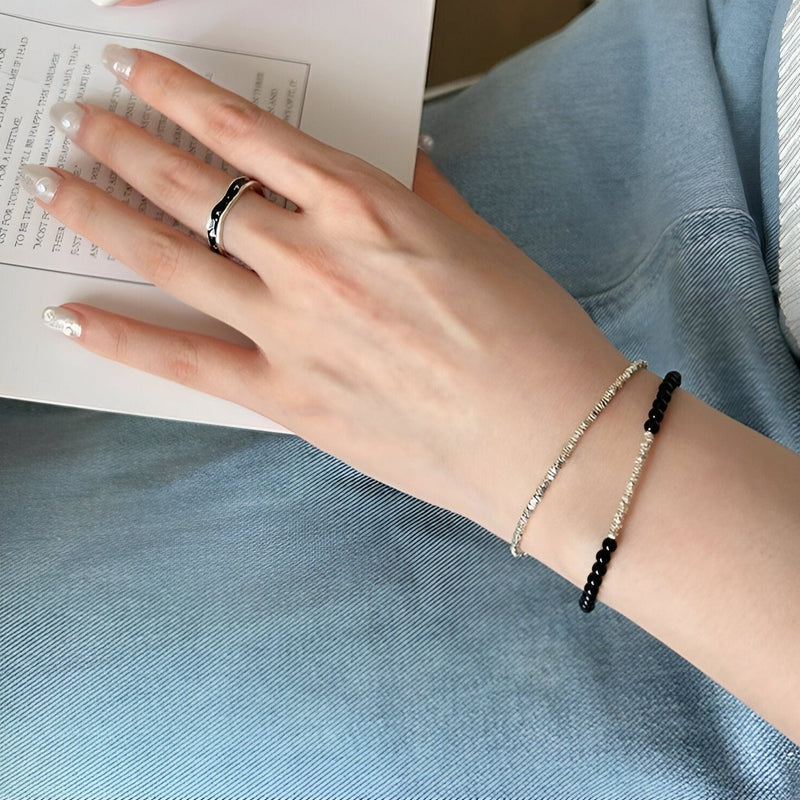 Bracelet fin en argent sterling avec perles d'onyx noires porté au poignet féminin.