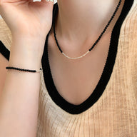 Bracelet en argent sterling et perles d'onyx noires porté au poignet, style élégant et minimaliste.