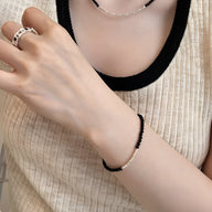 Bracelet fin en argent sterling avec pierres d'onyx noires, porté au poignet féminin.