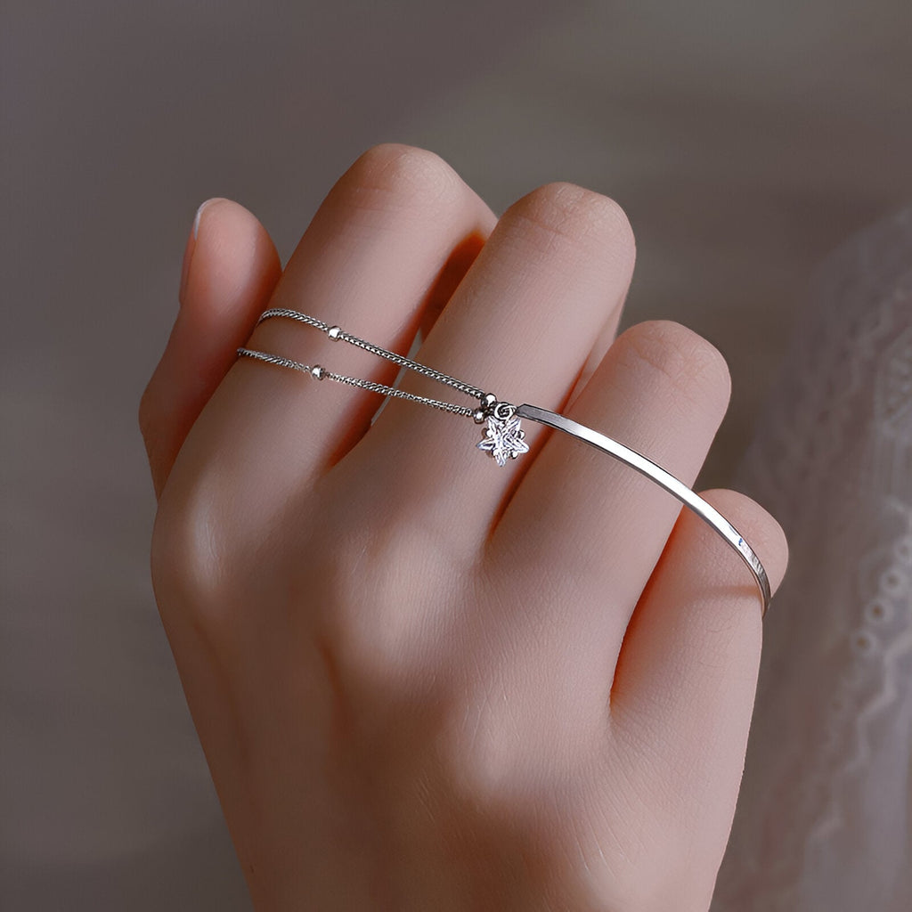 Bracelet fin en argent sterling avec étoile scintillante porté sur la main féminine.