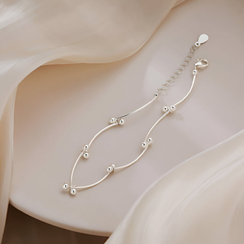 Bracelet en argent sterling fin avec motifs de noeuds perlés délicats et chaîne ajustable.