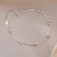Bracelet fin en argent sterling avec noeud et perles arrondies élégantes.
