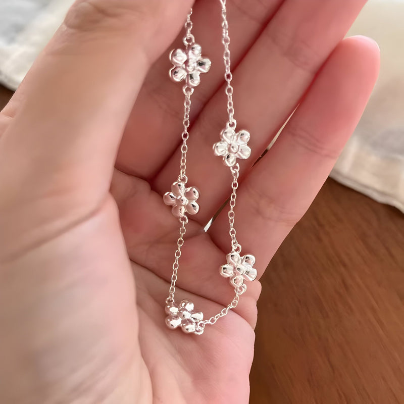 Bracelet fin en argent sterling avec quatre ornement de fleurs délicates en chaîne élégante.