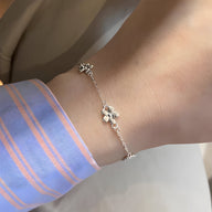 Bracelet fin en argent sterling avec pendentif ornement floral délicat porté au poignet.