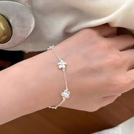 Bracelet fin en argent sterling avec petits ornements floraux délicats, porté au poignet féminin.