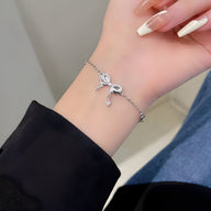 Bracelet fin en argent sterling avec ornement noeud délicat porté au poignet féminin.