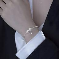 Bracelet en argent sterling avec ornement noeud délicat porté au poignet, style fin et élégant.