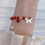 Bracelet argent sterling avec perles d'agate rouge et pendentif papillon sur poignet féminin.