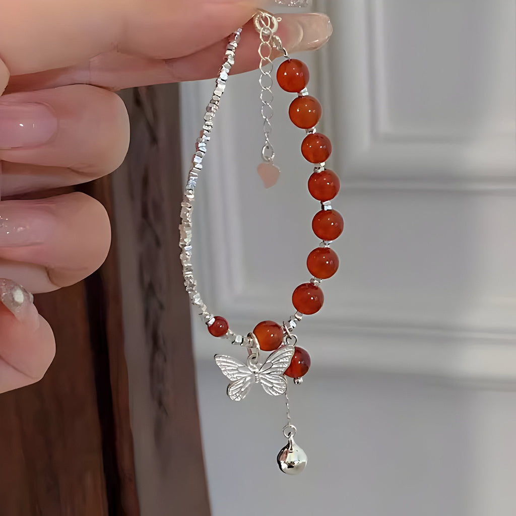 Bracelet argent sterling avec perles d'agate rouge, pendentif papillon et clochette suspendue.