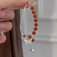 Bracelet argent sterling avec perles d'agate rouge, pendentif papillon et clochette suspendue.