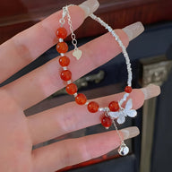 Bracelet en argent avec perles d'agate rouge et breloque papillon élégante.