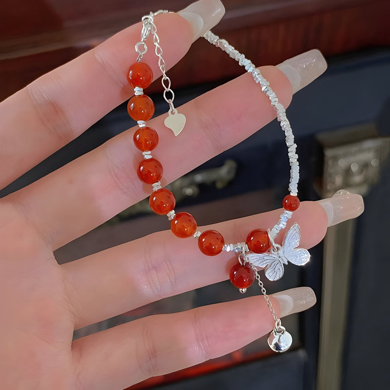 Bracelet en argent avec perles d'agate rouge et breloque papillon élégante.