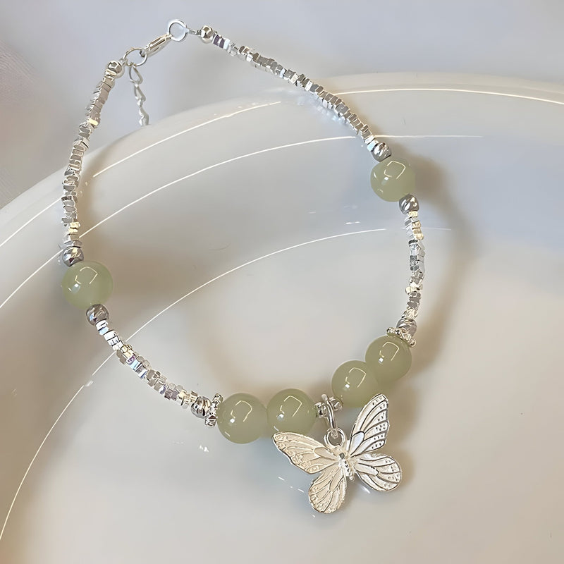 Bracelet argent sterling avec pierres de jade vert pâle et pendentif papillon détaillé.