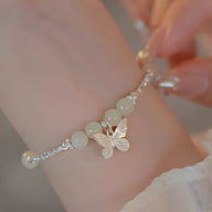 Bracelet argent sterling avec perles de jade blanches et breloque papillon délicate.