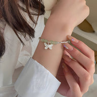 Bracelet en argent sterling avec pierres de jade vert clair et pendentif papillon blanc porté au poignet féminin.