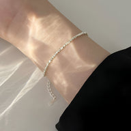 Bracelet fin en argent sterling avec petites perles brillantes, style élégant et délicat.