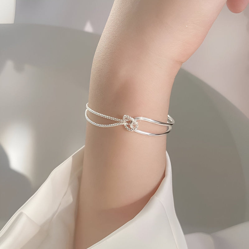 Bracelet fin en argent sterling avec petit nœud minimaliste porté au poignet féminin.