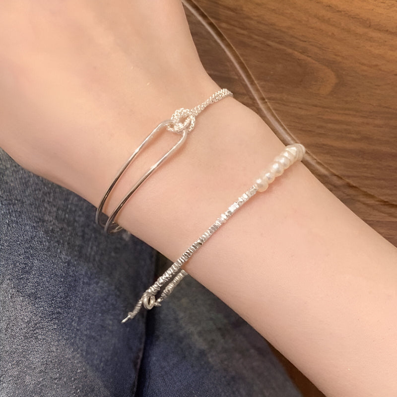 Bracelet en argent sterling avec noeud minimaliste porté au poignet, finition brillante.