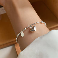 Bracelet argent sterling fin avec breloque cœur brillant et petits motifs ronds, style délicat pour femme.