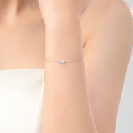 Bracelet fin en argent sterling avec charm cœur élégant porté au poignet féminin.