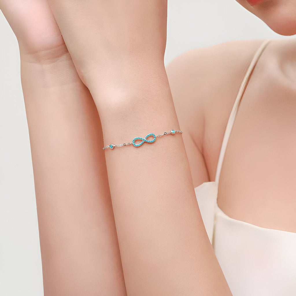 Bracelet en argent sterling avec charme infini orné de pierres turquoise lumineuses, style délicat féminin.