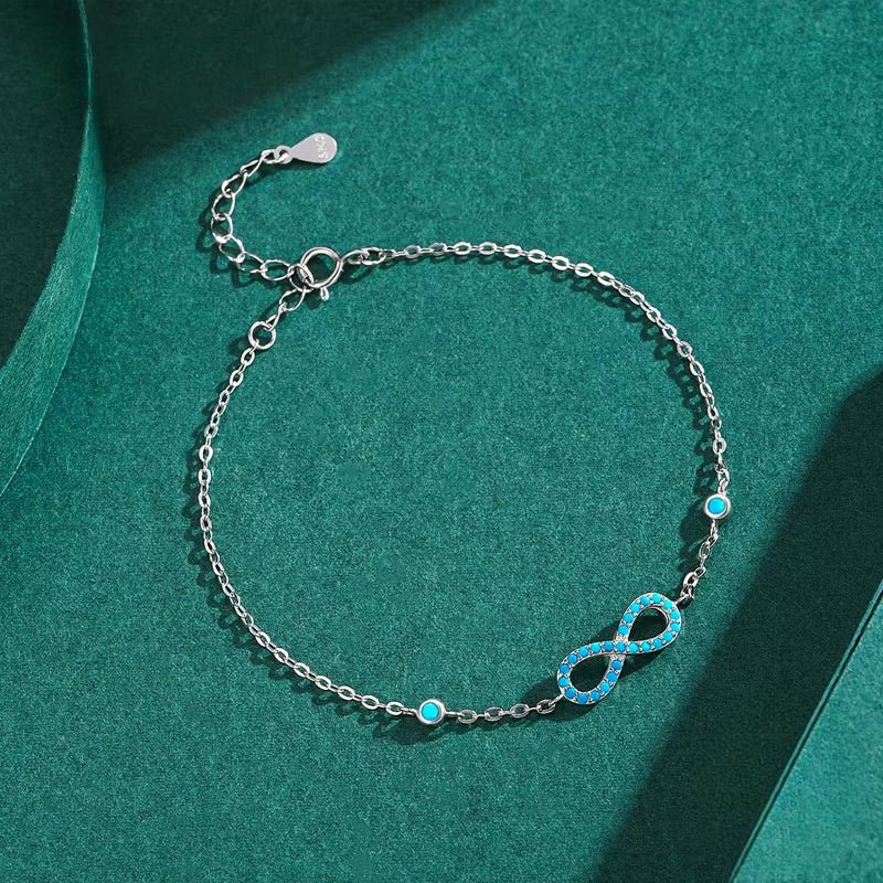 Bracelet en argent avec pendentif infini orné de turquoises, chaîne fine ajustable.