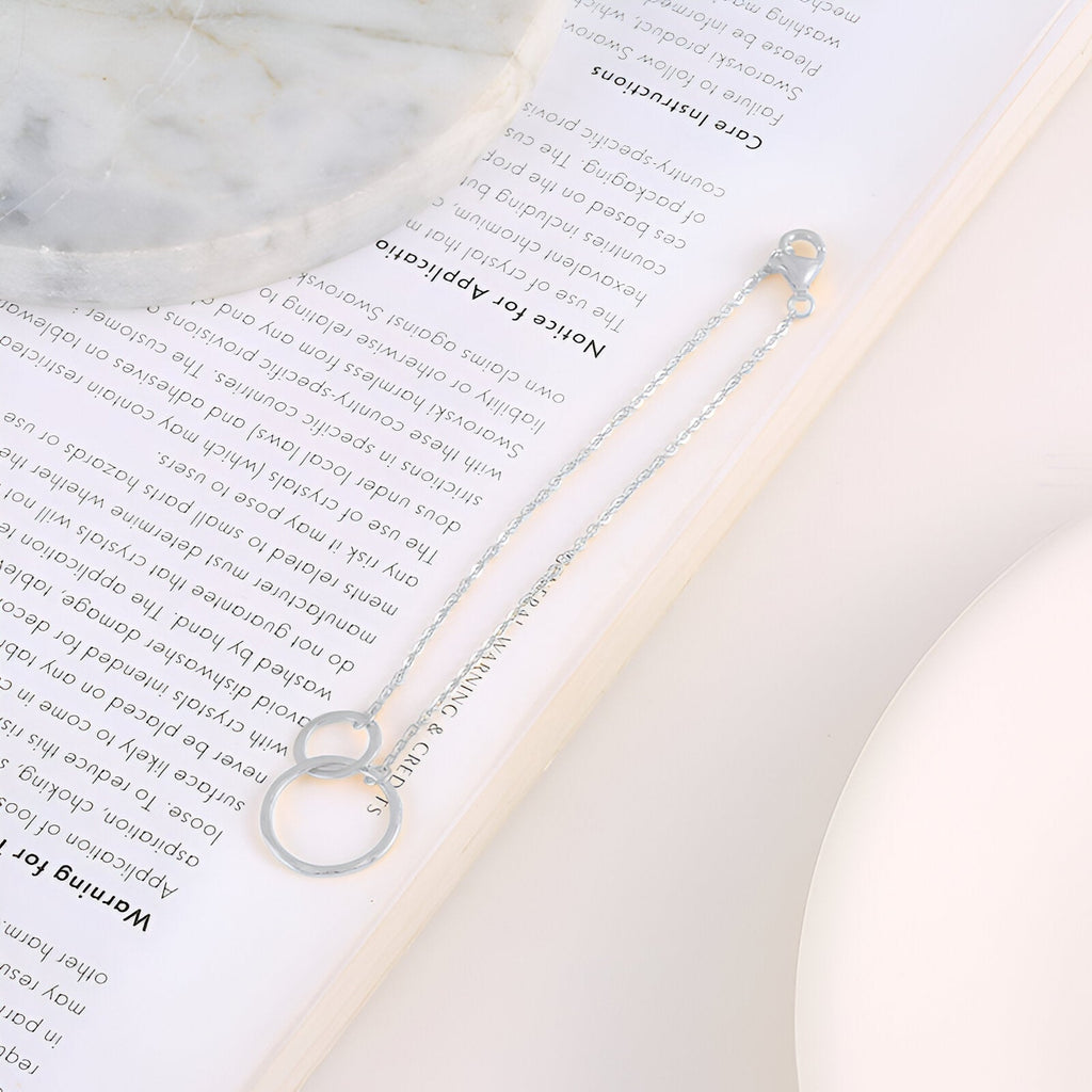 Bracelet en argent sterling pour femme avec deux cercles entrelacés et chaîne fine élégante.