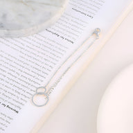Bracelet en argent sterling pour femme avec deux cercles entrelacés et chaîne fine élégante.