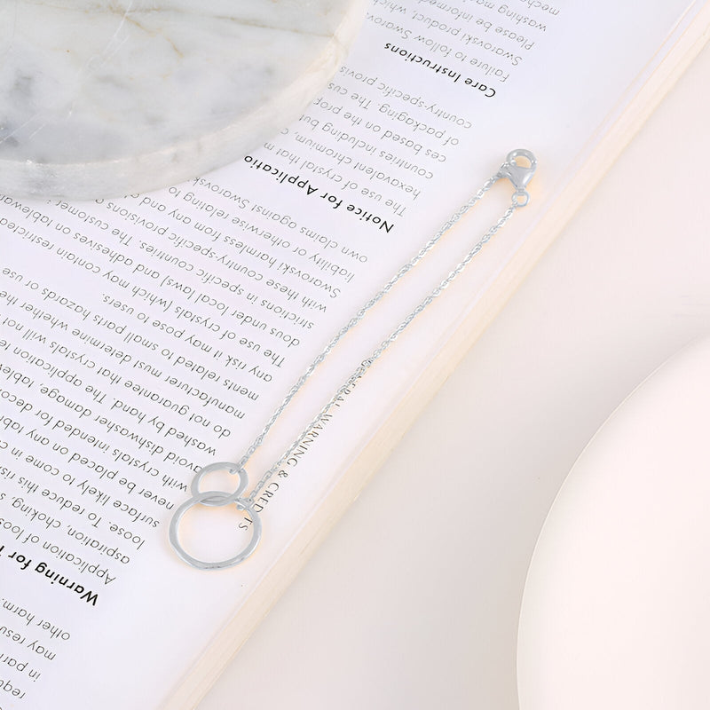 Bracelet en argent sterling pour femme avec deux cercles entrelacés et chaîne fine élégante.