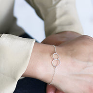 Bracelet fin en argent sterling avec deux cercles entrelacés sur poignet féminin.