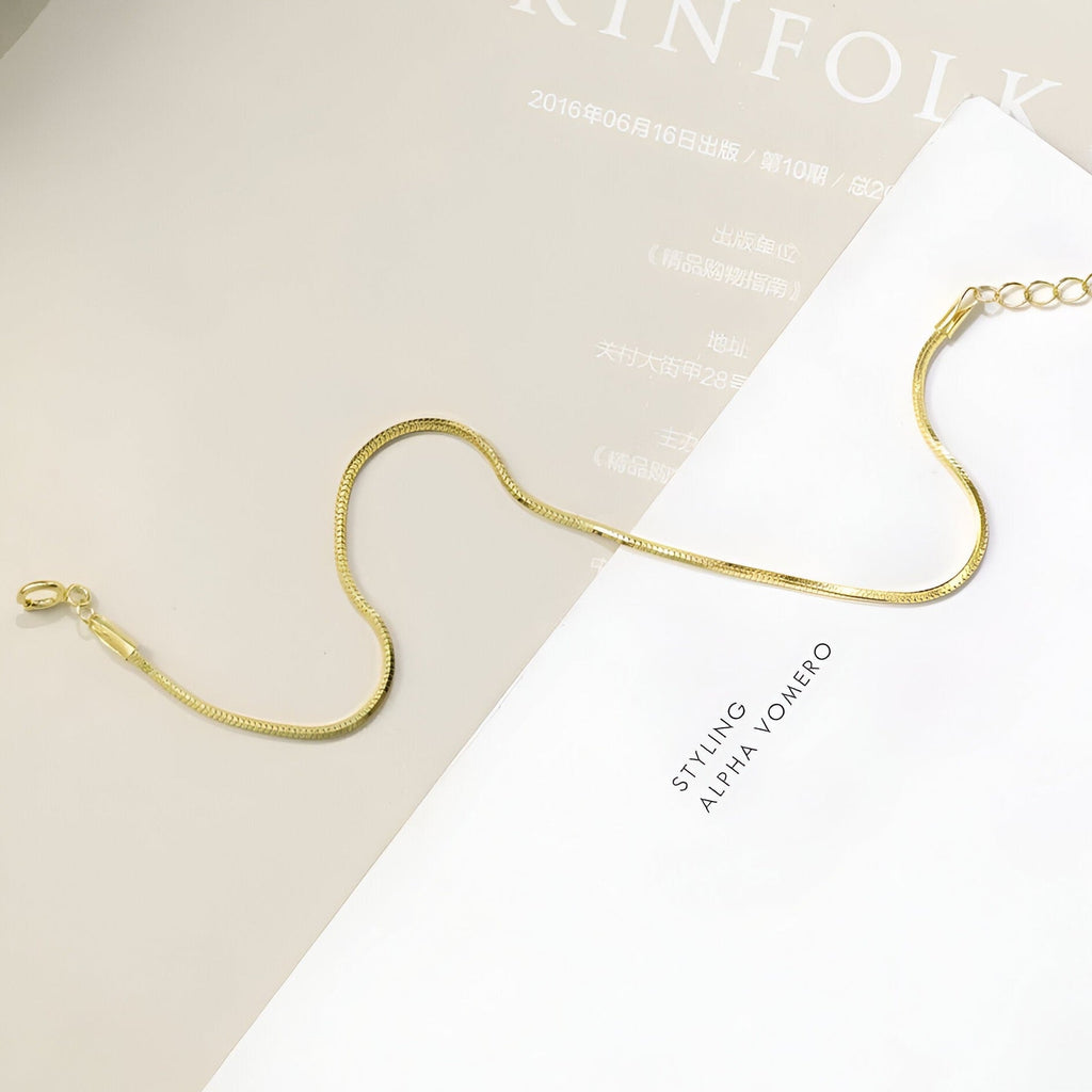 Bracelet fin en or jaune avec chaîne serpent et fermoir mousqueton, design élégant.