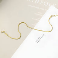 Bracelet fin en or jaune avec chaîne serpent et fermoir mousqueton, design élégant.