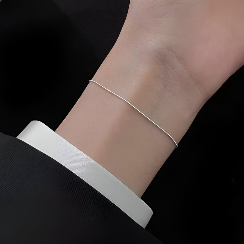 Bracelet fin en argent sterling pour femme porté au poignet, style minimaliste et élégant.
