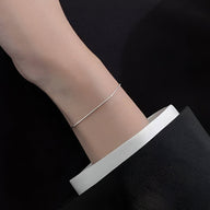 Bracelet fin en argent sterling brillant porté au poignet féminin, style minimaliste élégant.