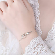 Bracelet en argent sterling fin avec pendentifs lapin et carotte délicats sur poignet féminin.