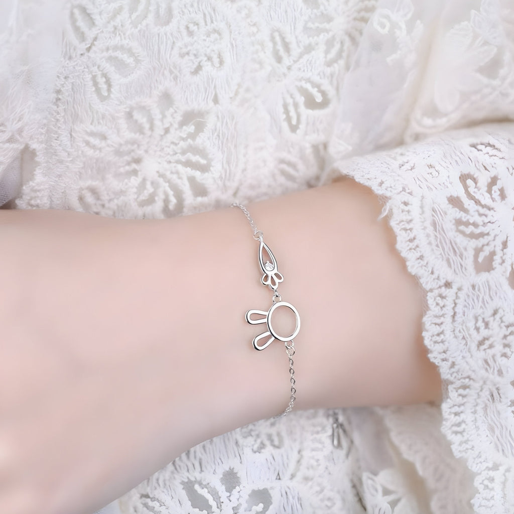 Bracelet en argent sterling avec pendentif lapin et carotte délicat porté sur poignet féminin en dentelle blanche.