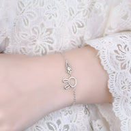 Bracelet en argent sterling avec pendentif lapin et carotte délicat porté sur poignet féminin en dentelle blanche.