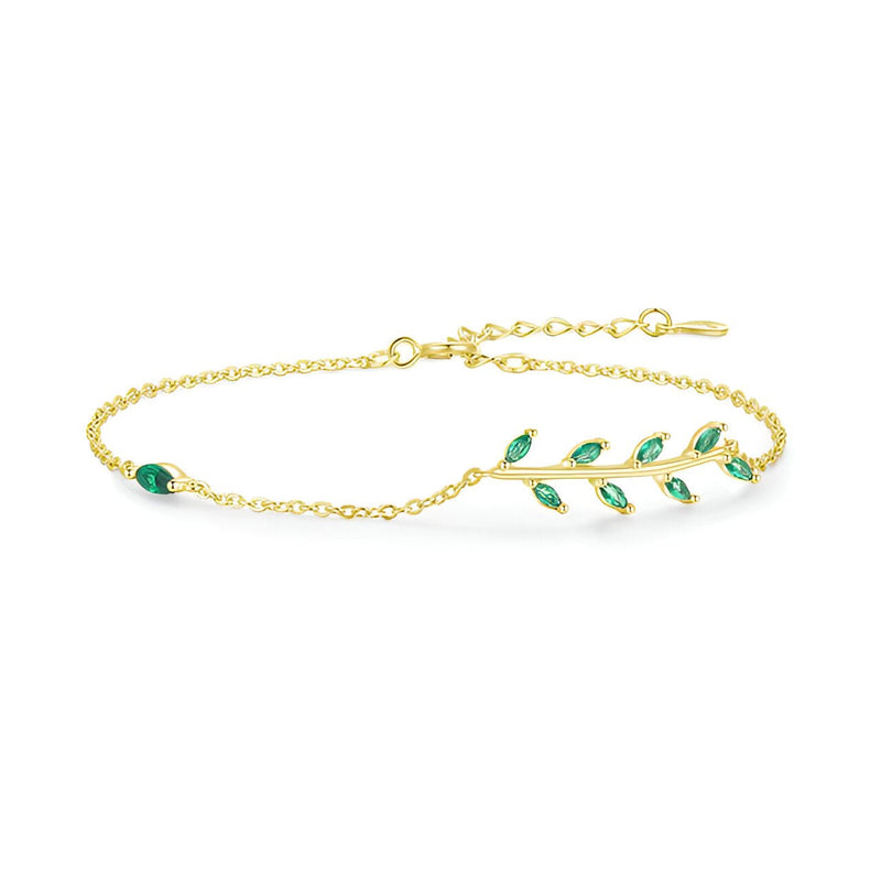Bracelet doré fin avec motif feuille ornée de petites pierres vertes sur chaîne délicate.