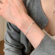 Bracelet argent sterling fin avec noeuds ruban délicats porté au poignet femme.