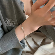 Bracelet en argent sterling fin avec noeud ruban délicat porté au poignet féminin.