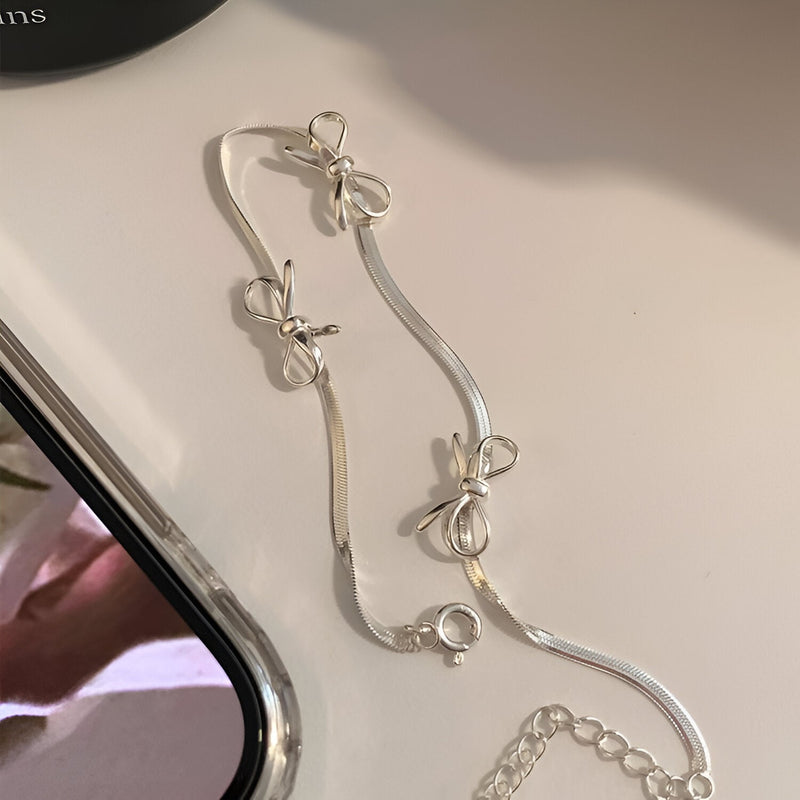 Bracelet en argent sterling fin avec trois noeuds ruban délicats, fermoir mousqueton.